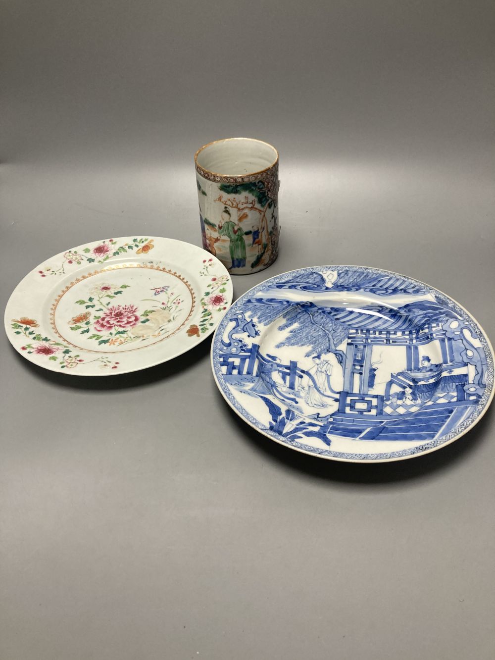 An 18th century Chinese famille rose plate together with a Chinese blue and white plate and a famille rose mug lacking handle, largest